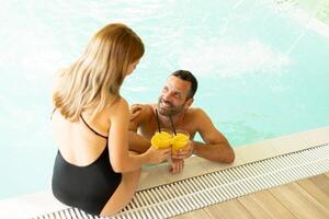 Jeune couple relaxant par le intérieur nager bassin photo