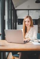 Jeune content affaires femme en utilisant portable ordinateur dans moderne bureau, élégant magnifique directeur souriant, travail sur financier et commercialisation projets. photo