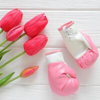 tulipes fleurs et boxe gants sur en bois arrière-plan, féminisme concept photo