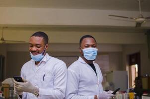 surexcité deux africain médecins en fonctionnement leur téléphone photo