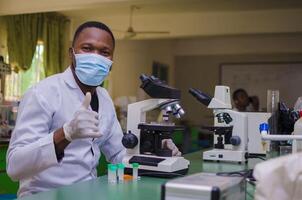 professionnel Beau Masculin scientifique travail sur une vaccin dans une scientifique recherche laboratoire et fait les pouces en haut photo