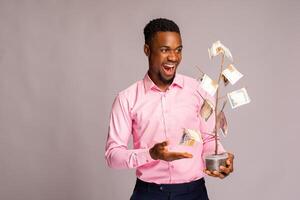 Beau africain homme eu surpris comme il détient une argent arbre. photo