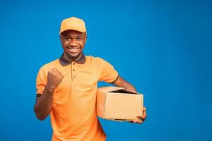 Beau africain gars sentiment excité comme il détient le livraison paquet sur le sien main photo