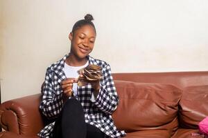 africain américain femme compte argent dans vivant pièce photo