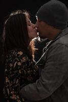 couple baiser sur une foncé Contexte avec une lumière cette les frontières leur silhouette. photo