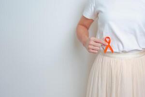 femme ayant retour abdomen douleur avec Orange ruban. un rein cancer conscience Mars mois, maladie de urinaire système et des pierres, cancer, chronique rein, urologie, rénal et transplantation concept photo