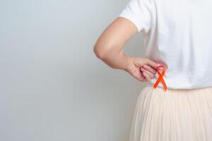 femme ayant retour abdomen douleur avec Orange ruban. un rein cancer conscience Mars mois, maladie de urinaire système et des pierres, cancer, chronique rein, urologie, rénal et transplantation concept photo