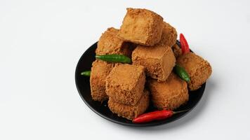 frit Tofu sur une noir assiette avec piments dans une blanc Contexte photo