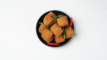 frit Tofu sur une noir assiette avec piments dans une blanc Contexte photo