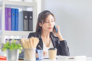 affaires femme en utilisant téléphone intelligent dans bureau. excité jolie fille en utilisant mobile Téléphone (s dans bureau, femme travail dans le Bureau photo