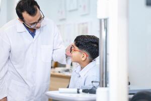 enfant indien choisissant des lunettes dans un magasin d'optique, garçon faisant un examen de contrôle des yeux avec un optométriste dans un magasin d'optique, optométriste faisant des tests de vue pour un enfant patient dans une clinique photo