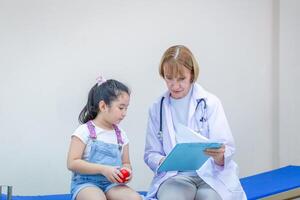 femelle médecin examiner une peu mignonne fille, enfant sur consultation à le pédiatre. soins de santé et médicament concepts photo