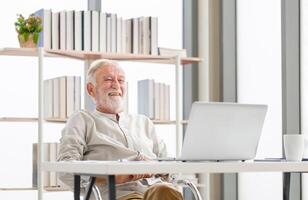 content Sénior homme avec portable et café tasse sur table profiter dans vivant chambre, mature homme dans le vivant pièce avec une portable photo