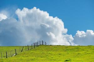 terres agricoles vertes génériques avec ciel bleu et nuages blancs moelleux derrière. photo