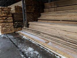 stockage de planches de bois sous un auvent avec de la neige et de la glace fondue sur le sol photo