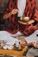 Tibétain en chantant bol dans le mains de une homme pendant une thé la cérémonie photo