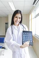 portrait d'une femme médecin intelligente tenant une tablette pour montrer une image radiographique et debout à la réception de l'hôpital. photo