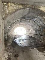 un vieux tunnel en dessous de le route à le autre fin vous pouvez voir le Soleil photo