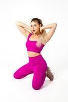 femme dans vibrant rose des sports tenue tous les deux les genoux sur sol, en portant mains sur cou photo