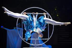 deux acrobate les filles spectacle une cirque nombre sur une foncé Contexte. acrobatique performance. photo