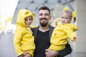 du père journée. content papa en portant deux petit les enfants dans le sien bras. photo