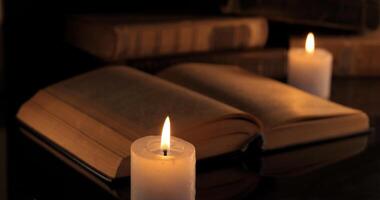 un vieux livre et brûlant bougies. en train de lire et apprentissage par aux chandelles à nuit photo