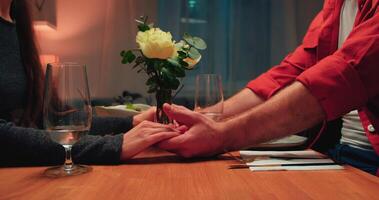 couple en portant mains ensemble à table pendant romantique dîner dans restaurant, fermer photo