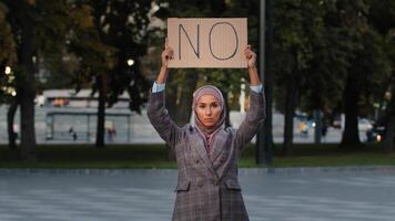 Arrêtez racisme concept arabe immigrant musulman femme dans hijab protestations contre la discrimination vax vaccination permanent dans ville. islamique fille en portant papier carton slogan bannière avec texte non être en désaccord refus photo