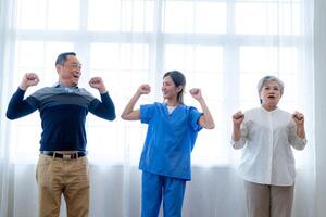 portrait de personnes âgées souriant asiatique femme et gens aérobie dans garderie maison. les personnes âgées sont en mouvement leur corps bras et épaules pour une en bonne santé vie. retraité gens Activités groupe concept. photo