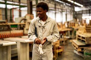 africain homme ouvriers ingénierie permanent avec confiance avec travail suite robe et main gant dans de face machine. concept de intelligent industrie ouvrier en fonctionnement. bois usine produire bois palais. photo