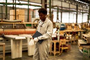 africain homme ouvriers ingénierie permanent avec confiance avec travail suite robe et main gant dans de face machine. concept de intelligent industrie ouvrier en fonctionnement. bois usine produire bois palais. photo