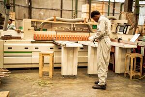 africain homme ouvriers ingénierie permanent avec confiance avec travail suite robe et main gant dans de face machine. concept de intelligent industrie ouvrier en fonctionnement. bois usine produire bois palais. photo