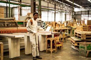 africain homme ouvriers ingénierie permanent avec confiance avec travail suite robe et main gant dans de face machine. concept de intelligent industrie ouvrier en fonctionnement. bois usine produire bois palais. photo