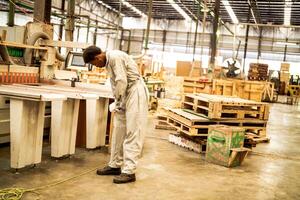 africain homme ouvriers ingénierie permanent avec confiance avec travail suite robe et main gant dans de face machine. concept de intelligent industrie ouvrier en fonctionnement. bois usine produire bois palais. photo