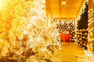 couvert de neige Noël arbre avec brillant blanc lumières situé en plein air près une bâtiment, une accueillant de fête moment. photo