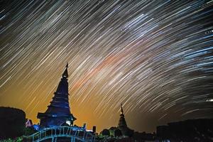 traînées d'étoiles la nuit au-dessus de la silhouette de la pagode en thaïlande. photo