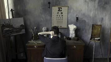 arrière vue de une homme travail sur ordinateur dans le art studio avec une peinture, plâtre sculptures, et brosses sur béton stylisé mur Contexte. Stock images. Masculin dans le art atelier. photo