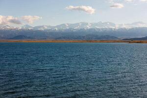 bleu calme l'eau dans issyk-kul Lac avec montagnes sur Contexte à l'automne après midi photo