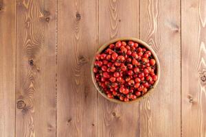 rouge chien-rose rose musquée des fruits dans une en bois bol sur en bois table photo