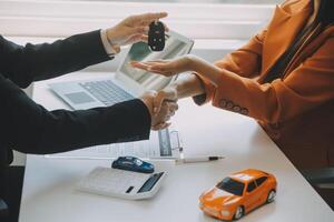 fermer asiatique Masculin gens voiture vendeur ou Ventes directeur des offres à vendre une voiture et explique et lit le termes de signature une voiture Contrat et assurance. photo