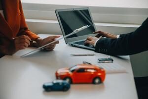 fermer asiatique Masculin gens voiture vendeur ou Ventes directeur des offres à vendre une voiture et explique et lit le termes de signature une voiture Contrat et assurance. photo