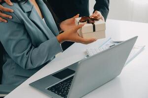 Jeune homme d'affaire donnant le sien collègue présent dans bureau. Jeune homme surprise magnifique femme d'affaires dans bureau. photo