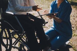 allaitement Personnel parlant à un personnes âgées la personne séance dans une fauteuil roulant. photo