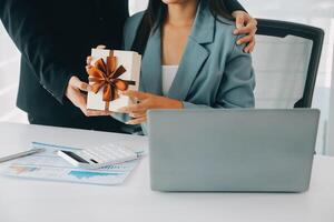 Jeune homme d'affaire donnant le sien collègue présent dans bureau. Jeune homme surprise magnifique femme d'affaires dans bureau. photo