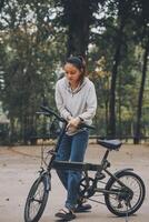 content asiatique Jeune femme marcher et balade vélo dans parc, rue ville sa souriant en utilisant bicyclette de transport, éco amical, gens mode de vie concept. photo