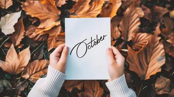 ai généré mains en portant une feuille de papier avec le mot octobre dans l'automne feuilles Contexte photo