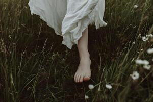 ai généré pieds de une fille dans une blanc robe sur une Contexte de vert herbe photo