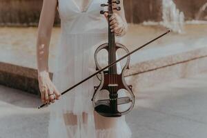 une fragment de un électrique violon, une violon dans le mains de une les musiciens fille photo