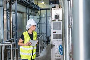 femelle industriel ingénieur portant une blanc casque tandis que permanent dans une lourd industriel usine photo