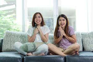 asiatique femme et ami asseoir à Accueil sur canapé lit regarder la télé film. photo